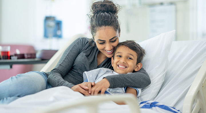 Young diverse mother hugging son in hospital bed