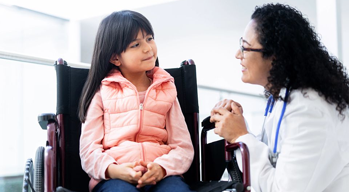 young girl in a wheelchair speaking with her doctor